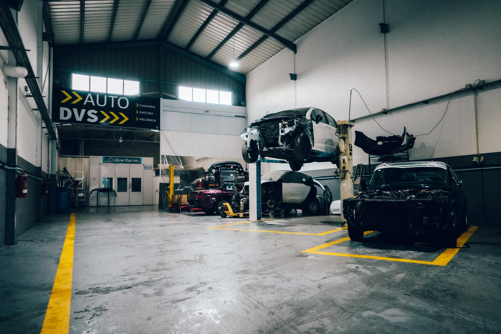 Interior da oficina AUTO DVS com automóveis em elevadores